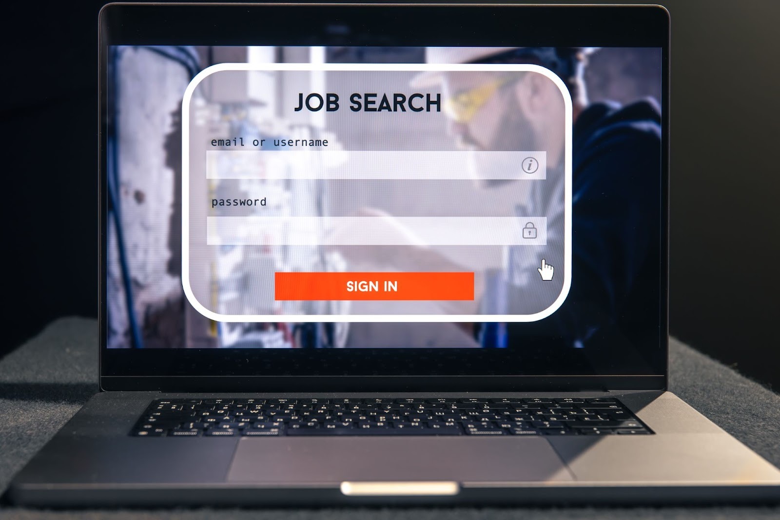 A laptop displaying a job search login screen with fields for email or username and password, along with a bright orange “Sign In” button on a blurred background.